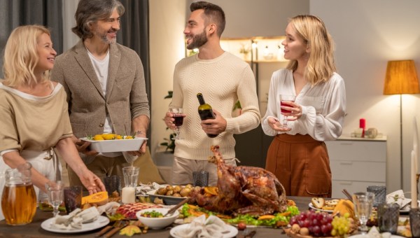 Happy young man with bottle and glass of red wine looking at his parents
