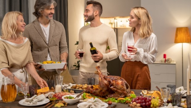 Happy young man with bottle and glass of red wine looking at his parents