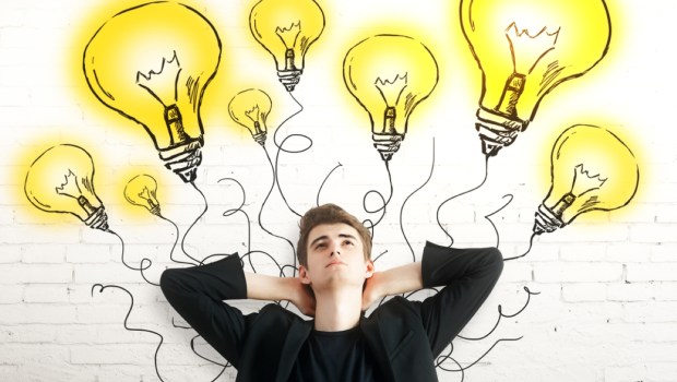 Thoughtful young man with light bulbs on brick background