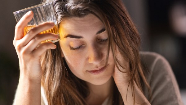 drunk woman or female alcoholic drinking whiskey at home