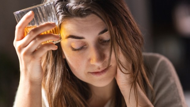 drunk woman or female alcoholic drinking whiskey at home