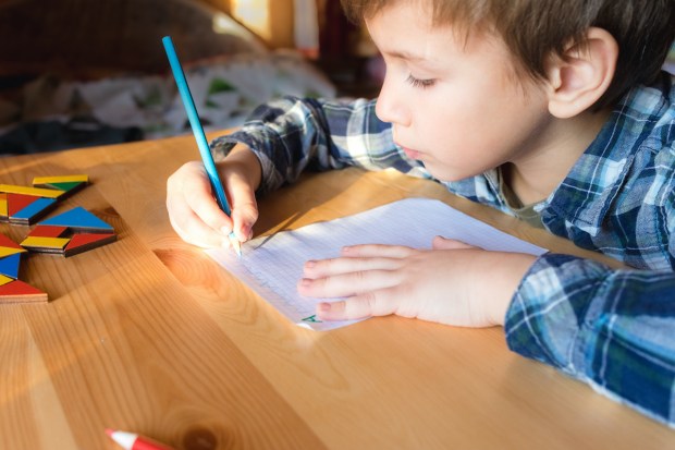 Little child sits by desk and doing lessons