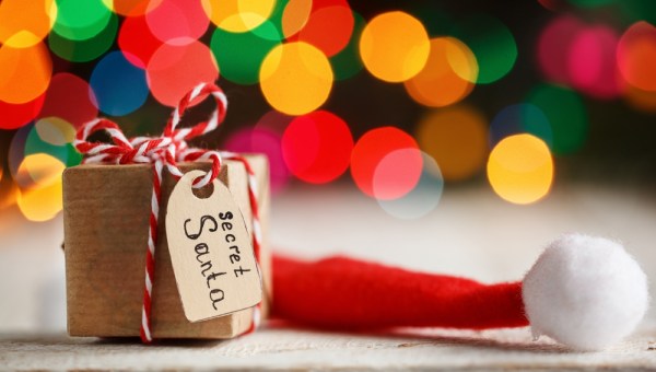 Christmas present or box for secret santa with Santa hat on colorful bokeh background