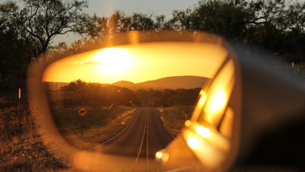 Looking at the mountains and sunset through rear view mirror