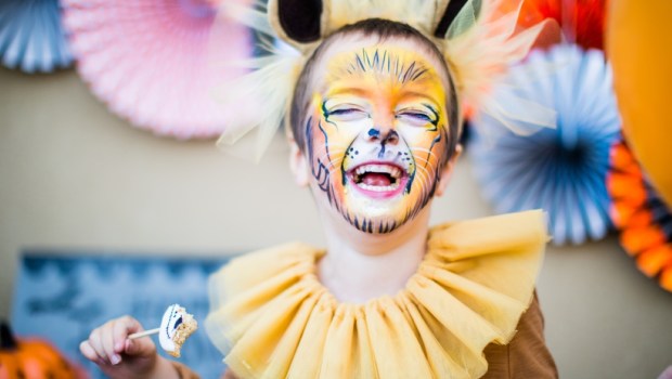 Boy in lion fancy dress laughing at children's halloween party