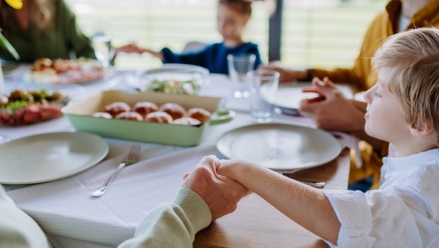 Close-up of family holding hands, praying before Easter lunch.