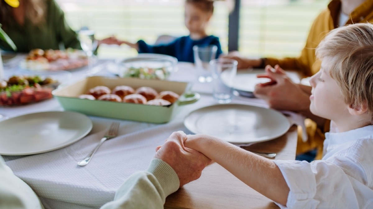 Close-up of family holding hands, praying before Easter lunch.