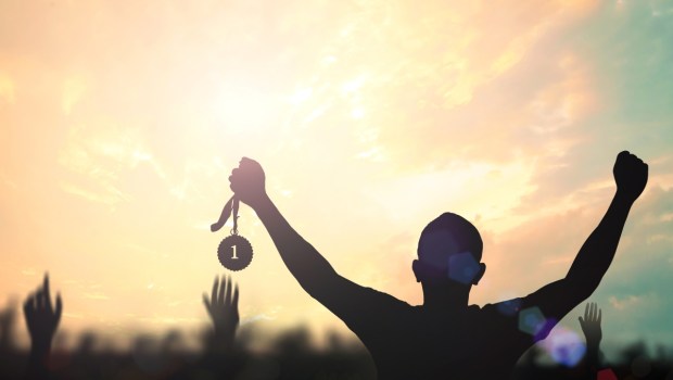 Silhouette champion hand holding gold medal reward