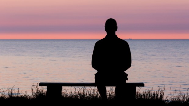 Silhouette of male person against a colorful horizon