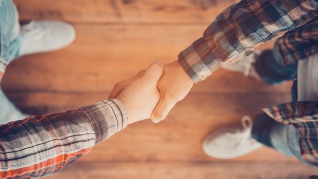 Top view of two men shaking hands while standing on the wooden floor