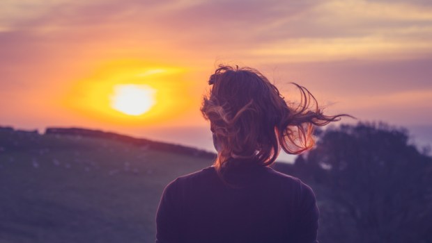 Young woman admiring the sunset over fields