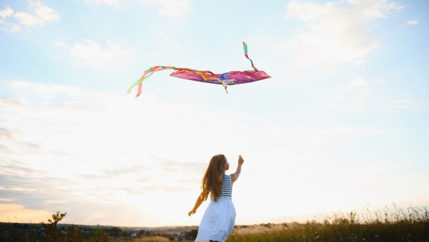 one happy little girl running on field with kite