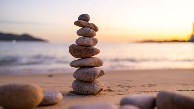 Balance pebble stone in the sand beach at sunset