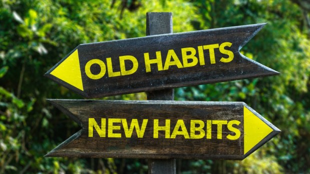 Old Habits - New Habits signpost with forest background