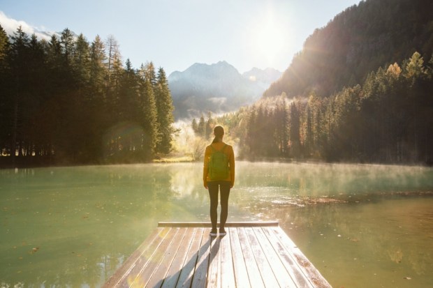 Young woman standing at the edge of a wooden pier at a mountain lake