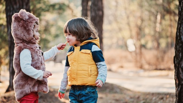 toddler girl giving cookie to her friend on the walk