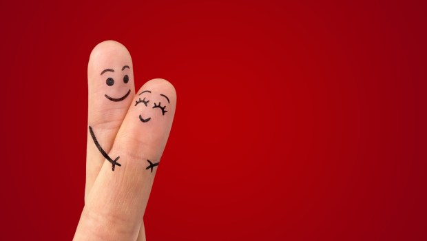 A happy couple in love with painted smiley and hugging
