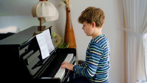 Beautiful little kid boy playing piano in living room
