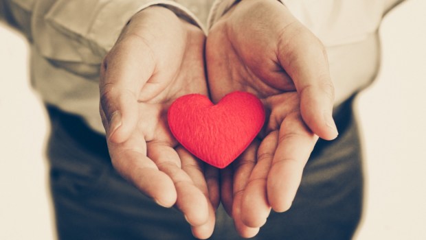 Businessman giving a red heart to a customer on isolated background