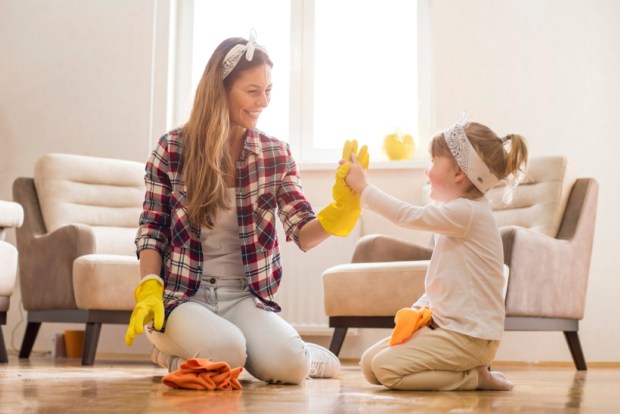 Daughter and mother cleaning home together and having fun
