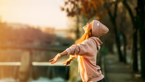 cool hipster young girl in pink hoodie standing by a river
