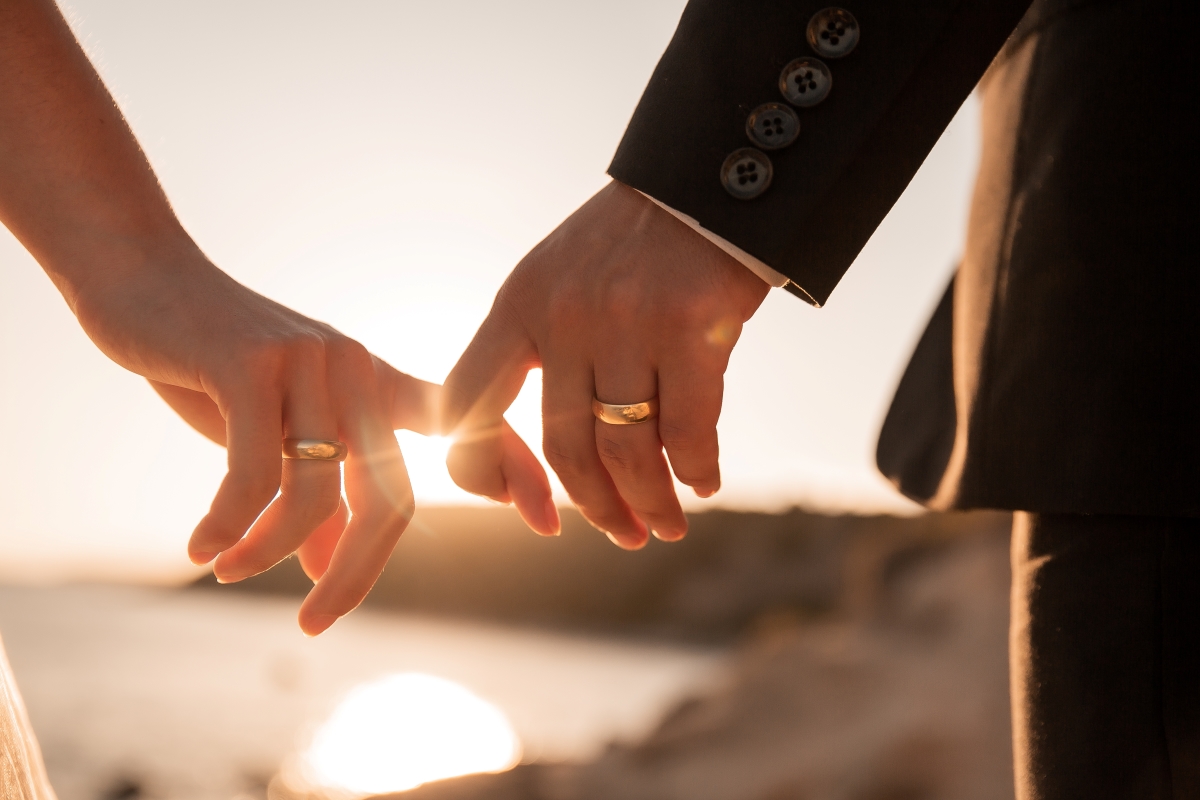 romantic couple holding hands fingers at sunset