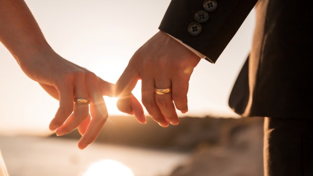 romantic couple holding hands fingers at sunset