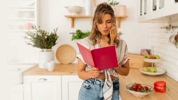 Funny housewife woman looking at recipe in cookery book