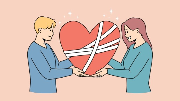 Happy man and woman hold in hands fixed broken heart with bandages on surface