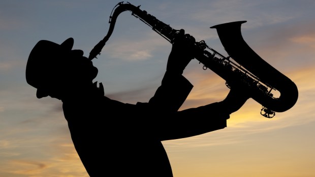 Man playing on saxophone against the background of sunset