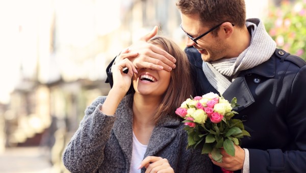 Picture of young man surprising woman with flowers