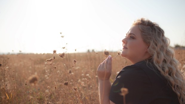 Portrait of beutiful plus size woman walks outdoor against the field and sunloght
