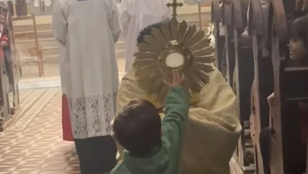 Le père Gil Passio présente le Saint-Sacrement à un petit garçon