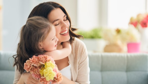 Child daughter congratulates mom and gives her flowers.