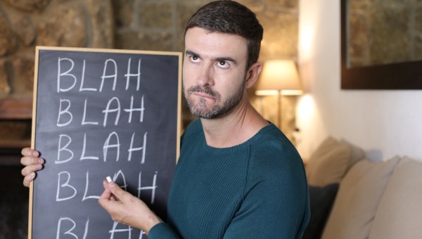 Man holding chalkboard with "blah blah blah" hand written