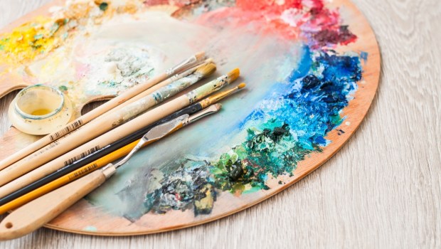 Materials for creativity, palette and brush for painting on a wooden background