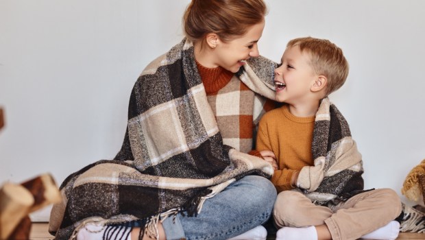 happy family mother and loving son hug and laugh wrapped in a warm blanket on a cozy winter evening at home