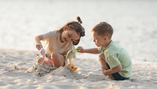 Children boy and girl playing on the beach on summer holidays