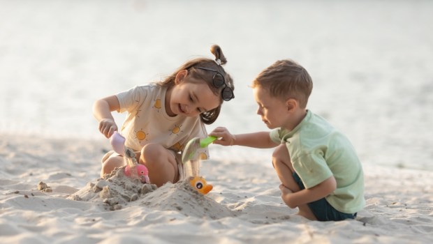 Children boy and girl playing on the beach on summer holidays