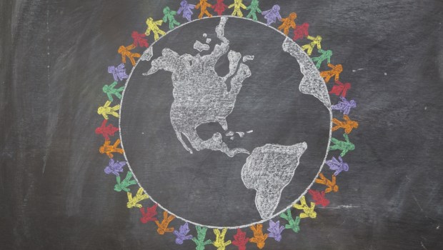 A hand drawn chalkboard shows multi-ratial people holding hands around the world
