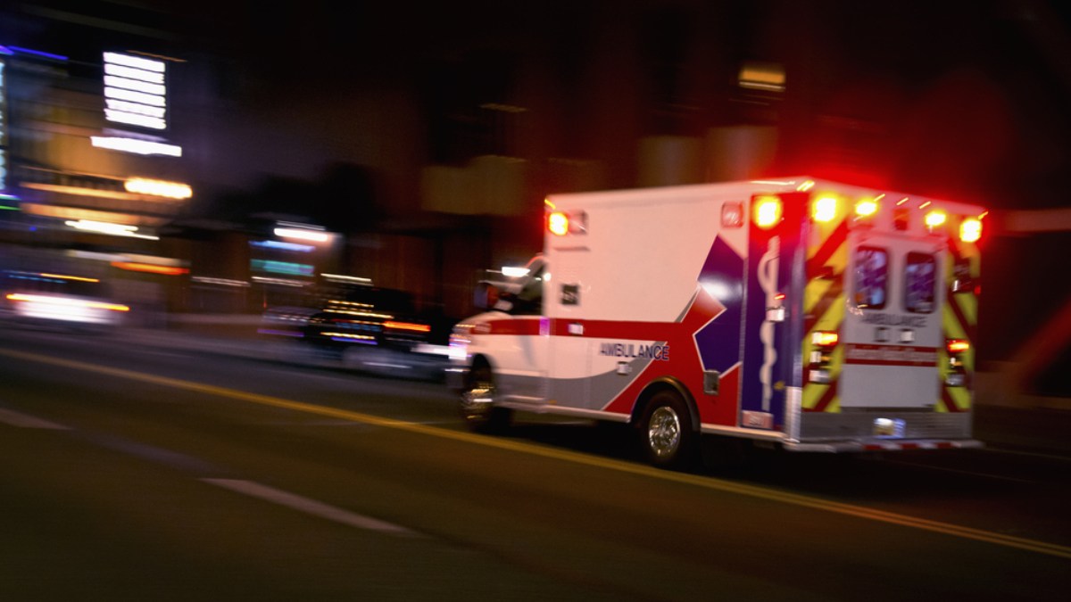 An ambulance speeding through traffic at nighttime