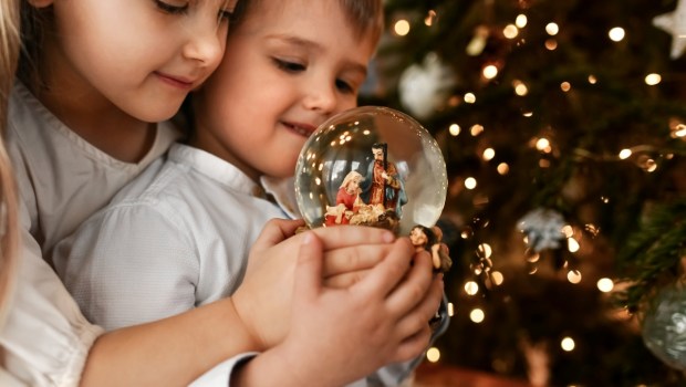 The kids looking at a glass ball with a nativity scene of the birth of Jesus Christ