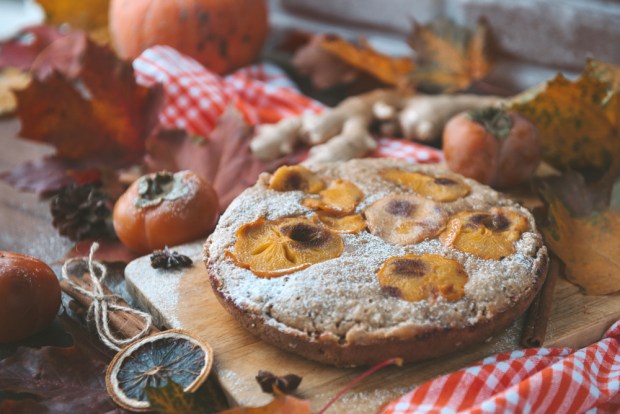 homemade cake with pieces of persimmon and powdered sugar, fresh persimmon, autumn fallen red leaves, pumpkin, cinnamon, ginger,