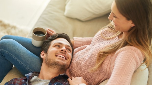 Coffee, relax or happy couple on sofa in home living room together with love, support or trust