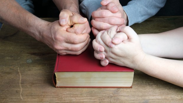 Dłonie ludzi złożone na Biblii
