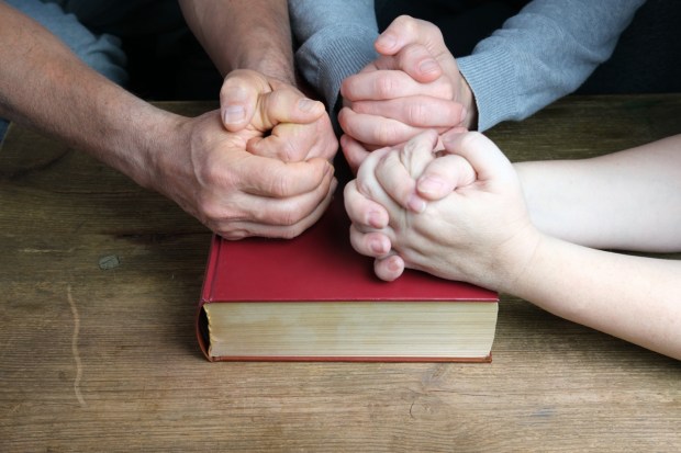 Dłonie ludzi złożone na Biblii