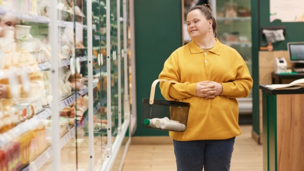 Portrait of smiling young woman with Down syndrome enjoying grocery shopping