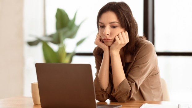 isappointed cute secretary using laptop sitting at desk in modern office
