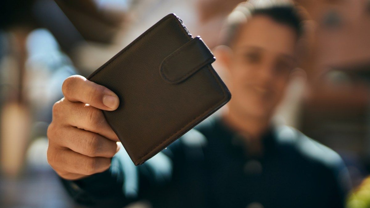 Young hispanic man smiling happy holding wallet at the city