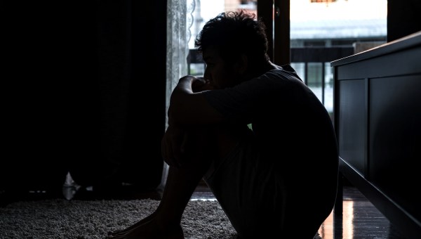 Depressed Asian man sitting on the floor